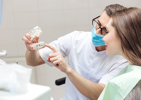 a dentist showing model teeth to a patient