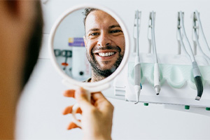 Dental patient admiring his new smile in mirror