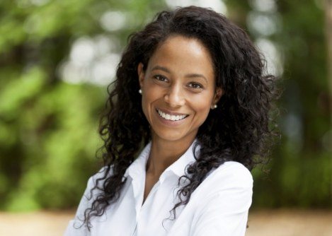 Woman in white collared shirt smiling outdoors