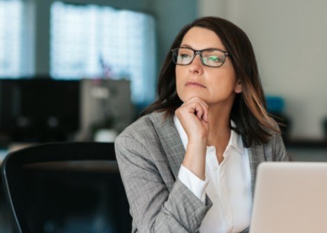 Woman looking pensive while sitting at desk with laptop