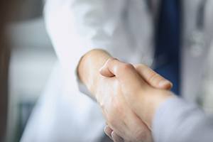 Close up of oral surgeon and patient shaking hands