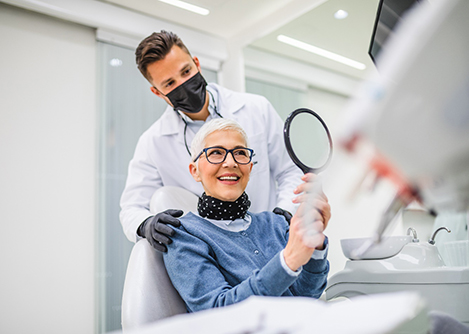 Patient smiling in mirror while holding handheld mirror