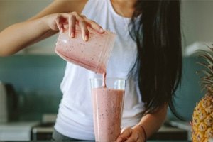 a woman preparing a fruit smoothie