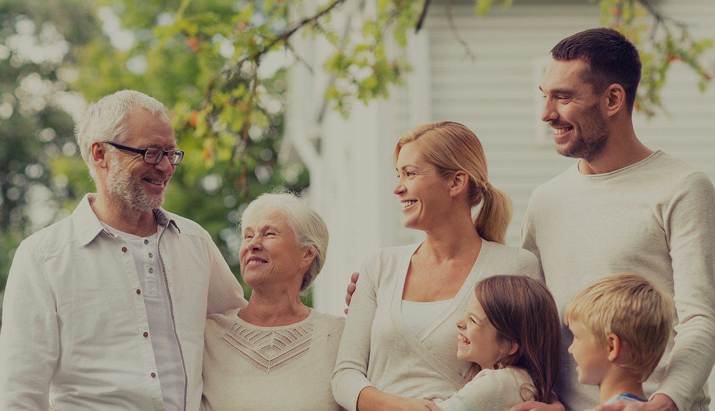 Two kids smiling outdoors with their parents and grandparents