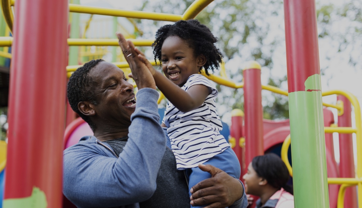 Dad giving his daughter high five on playground