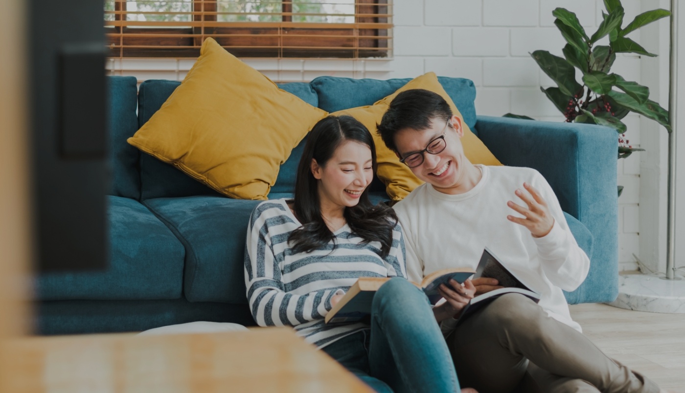 Man and woman sitting on living room floor reading books together