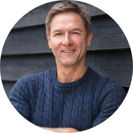 Smiling older man in dark blue sweater standing with arms crossed