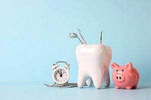 Tooth-shaped container holding dental tools next to piggy bank