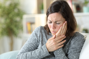a woman holding her cheek in pain